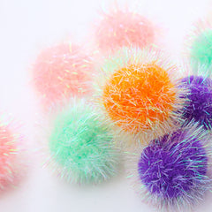 Osvela pelotas pom pom con brillo multicolor para estimulación visual diaria.