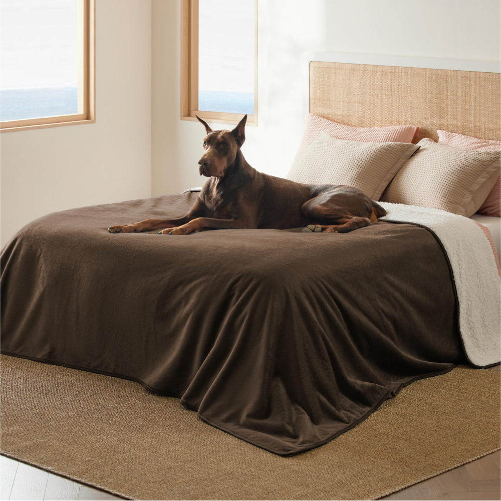 Bedsure manta impermeable con sherpa sobre cama, protege muebles de perros grandes.