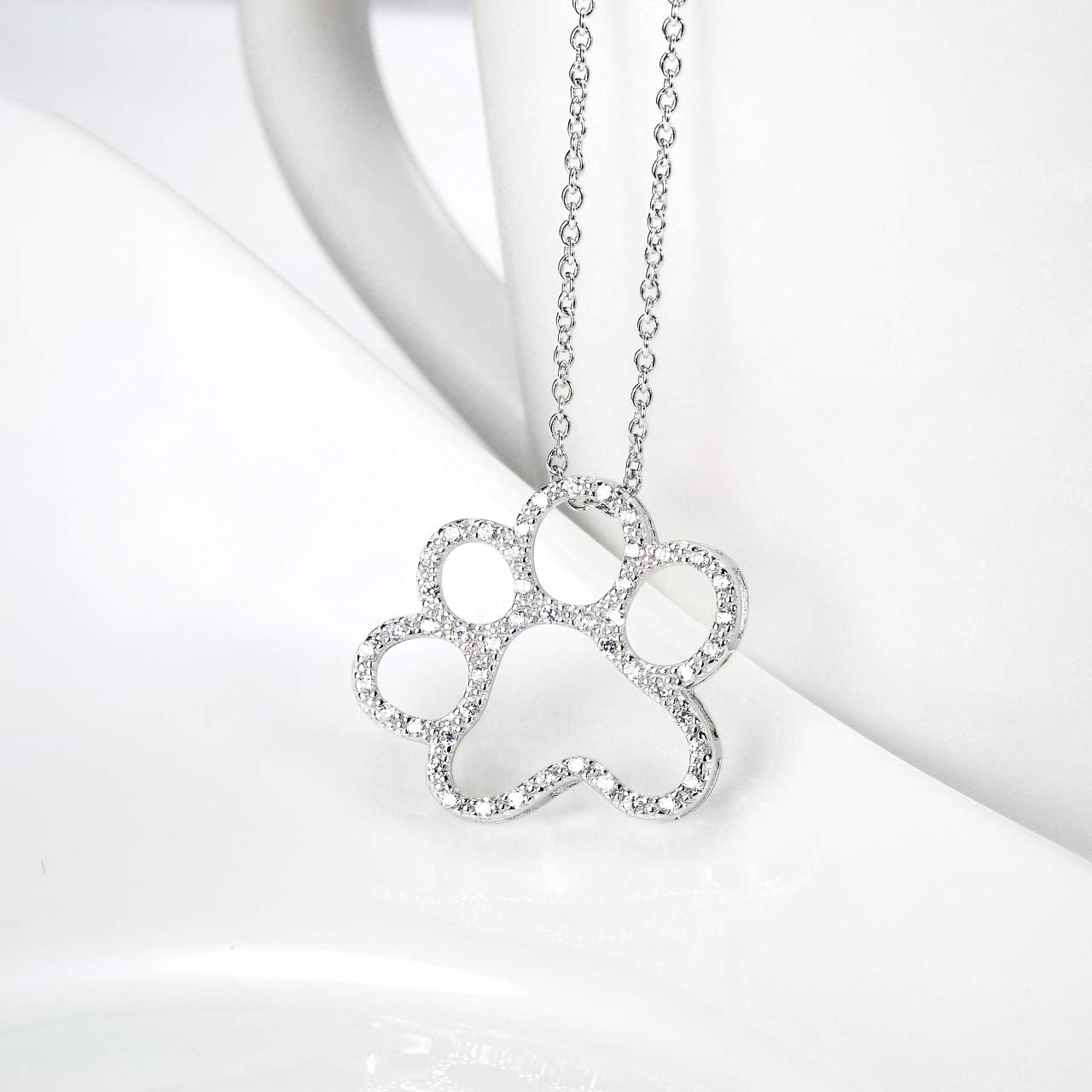 ONEFINITY detalle arte huella de perro en plata, enfoque artesanal que destaca.