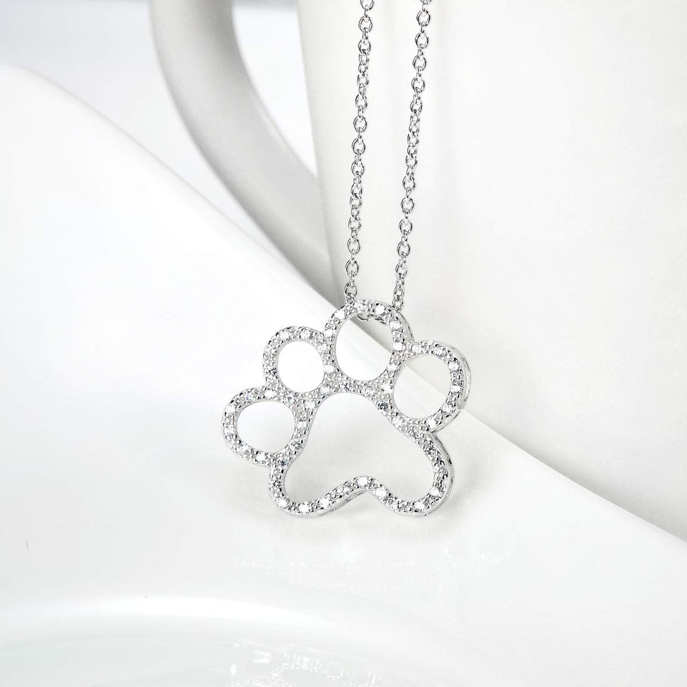 ONEFINITY detalle arte huella de perro en plata, enfoque artesanal que destaca.